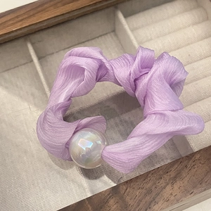 Close-up of a light purple chiffon hair scrunchie with an iridescent pearl in a jewelry box