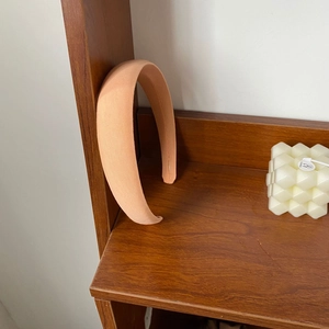 Padded wide light orange sponge headband for women with soft fabric on wooden shelf