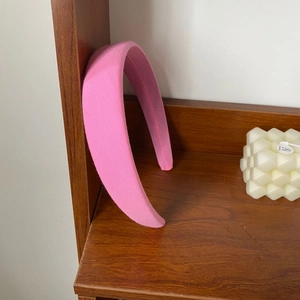 Minimalist thick pink sponge headband with soft fabric texture on a wooden stand