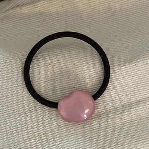 Minimalist pink pebble hair tie on canvas background with elastic black rope