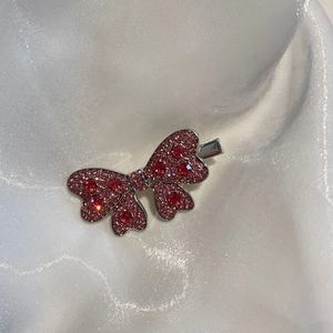 Détail d'une barrette à cheveux en forme de nœud scintillant avec strass roses et rouges