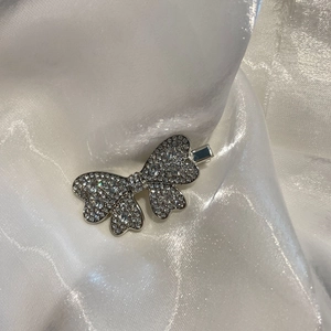 Barrette papillon argentée scintillante avec strass complets sur fond de satin blanc