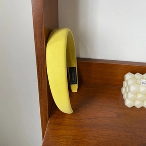 Detailed shot of yellow padded headband with handmade label on wooden shelf