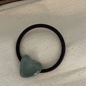 Detail view of a gray heart-shaped resin charm on a black high-elastic hair tie