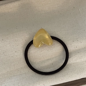 Detailed shot of yellow heart resin charm on a black elastic hair tie for women