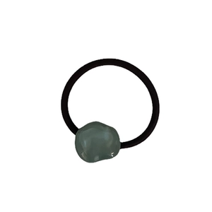 Minimalist black hair tie with a grey irregular resin geometric accent on white background