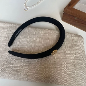 Detail showing the inner 'HAND MADE' label and golden rose emblem on a black sponge headband