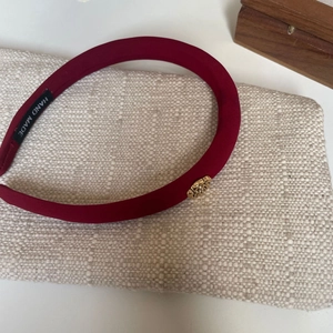 Detailed view of deep red fabric headband with handmade label and gold logo detail