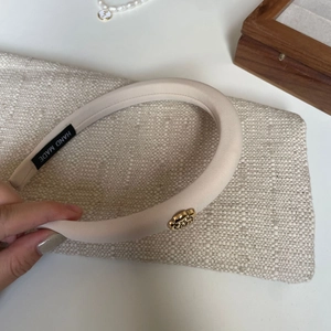Detail of handmade padded beige headband with vintage gold rose metal accent