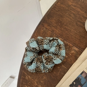 Close-up of blue and brown checkered tweed hair scrunchie on a rustic wooden table