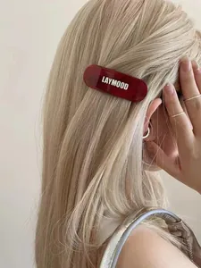 Detailansicht einer burgunderroten ovalen Acetat-Haarklammer auf blondem Haar