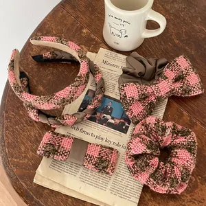 Detail of pink and brown plaid tweed hair accessories set on a wooden table surface