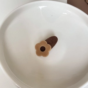Floral velvet hair clip in milk tea brown tones on a minimalist ceramic dish