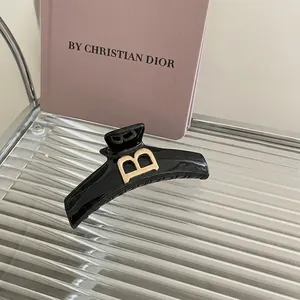 Pince à cheveux noire brillante minimaliste avec logo lettre B dorée élégante