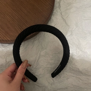 Detailed macro view of black ribbed knit headband showing the handmade brand label inside