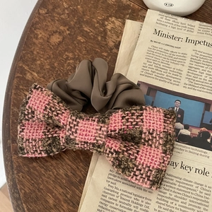 Pink and brown tweed bow scrunchie on vintage newspaper for a retro aesthetic style