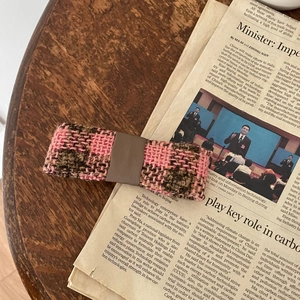 Pink and brown tweed checkered hair accessory on vintage newspaper and wooden background