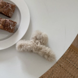 Minimalist beige plush hair claw clip for women in a cozy aesthetic setting