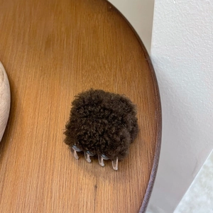 Détail de la pince à cheveux carrée en fausse fourrure marron avec texture bouclée