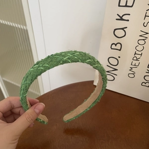 Detail of green tweed fabric headband with woven texture and non-slip lining