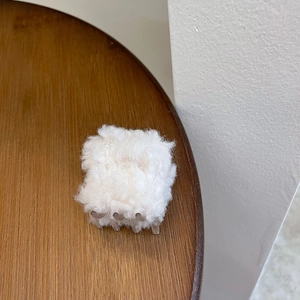 Gros plan d'une pince à cheveux en peluche blanche avec des dents transparentes