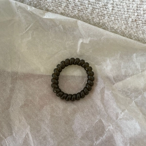 Dark coffee spiral hair coil for ponytail holders on textured white fabric background