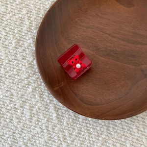 Detailed shot of a red acetate claw clip with a resin bear and white pearl detail
