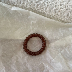 Deep brown spiral telephone wire hair tie for women on minimalist white background