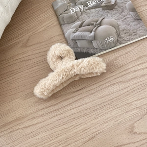 Große cremefarbene Plüsch-Haarklammer aus Kunstpelz für Damen auf einem Holzuntergrund