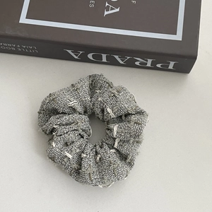 Close-up detail of grey tweed fabric texture and woven frayed edges of the headband