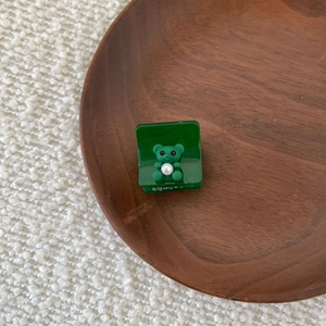 Detail of a dark green rectangular acetate hair claw clip with 3D bear and white pearl