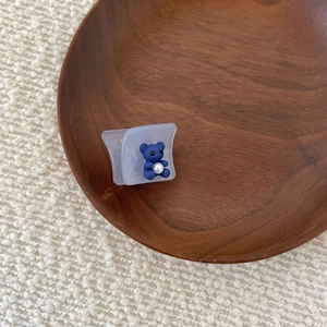 Detailed macro shot of a blue bear hair claw with a pearl accent on a wooden plate