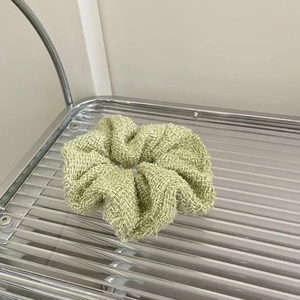 Detailed view of light green tweed scrunchie on a stylish silver metal rack accessory