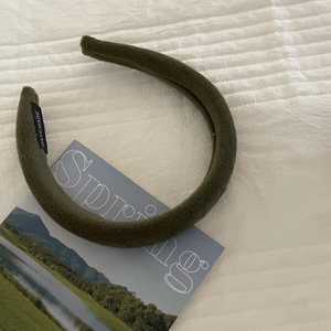 Detailed view of olive green velvet headband with a hand-made woven label on fabric