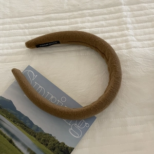Detail view of brown plush sponge headband with a handmade label on a magazine