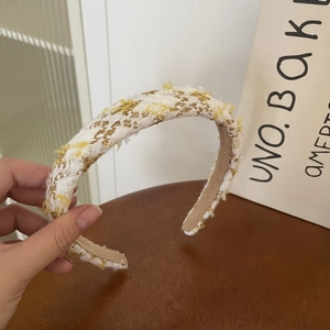 Close-up of yellow tweed headband with gold thread detail and textured fringe edge