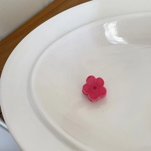 Nahaufnahme der rosa beflockten Blumen-Haarklammer mit samtiger Textur auf Teller