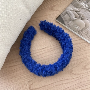 Close-up of deep blue plush lamb wool headband on a soft wooden background