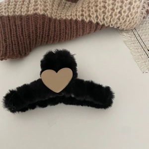 Detail of plush black faux fur claw clip with a beige heart accent for winter hair styling