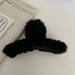 Close-up of black plush heart hair claw clip with soft faux fur texture for winter styles