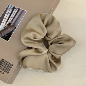 Close-up of premium champagne gold satin oversized scrunchie on a magazine