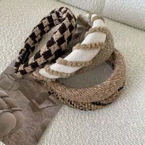 Close-up of brown tweed, white fuzzy, and sequined fabric headbands on white cloth
