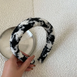 Close-up of black and white checkered knit headband with a Hand Made label detail