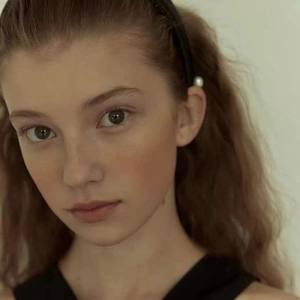 Elegant black velvet headband featuring a white pearl accent on a female model