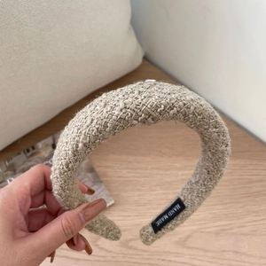 Detailed texture of thick beige tweed headband featuring a hand made fabric label