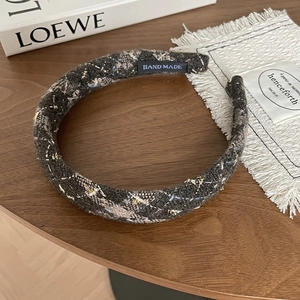 Padded grey tweed headband with golden metallic thread and handmade label on wood