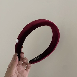 Detail of burgundy velvet sponge headband featuring a white pearl and handmade label