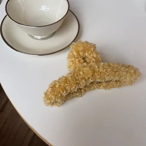 Gros plan sur une grande pince à cheveux en peluche camel sur un bureau blanc