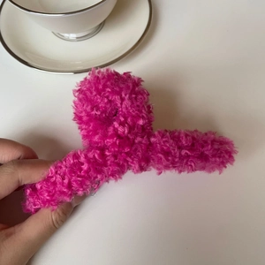 Gros plan d'une pince à cheveux en peluche rose fuchsia dans un décor élégant