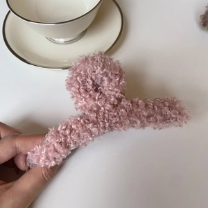 Détail de la grande pince à cheveux en peluche rose poudré avec texture bouclée